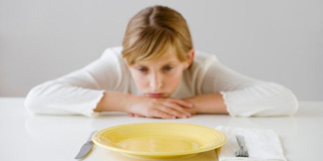 Teenaged girl looking at empty plate