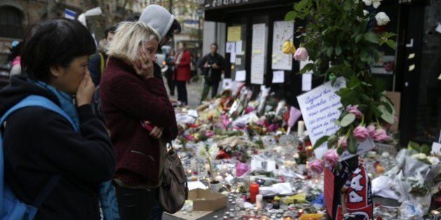 People spend a moment mourning the dead at the site of the attack at the Cafe Belle Equipe on rue de Charonne in the 11th district, prior to going to work early on November 16, 2015 in Paris, three days after the terrorist attacks that left over 130 dead and more than 350 injured. France prepared to fall silent at noon on November 16 to mourn victims of the Paris attacks after its warplanes pounded the Syrian stronghold of Islamic State, the jihadist group that has claimed responsibility for the slaughter. AFP PHOTO / KENZO TRIBOUILLARD (Photo credit should read KENZO TRIBOUILLARD/AFP/Getty Images)