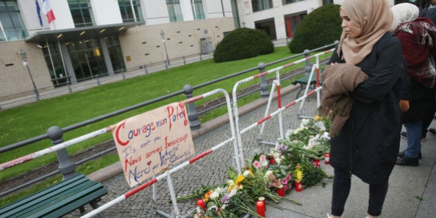 BERLIN, GERMANY - NOVEMBER 14: A young Muslim woman looks at flowers and candles left by mourners at the gate of the French Embassy following the recent terror attacks in Paris on November 14, 2015 in Berlin, Germany. Hundreds of people came throughout the day to lay flowers, candles and messages of condolence to mourn the victims of attacks last night in Paris that left at least 120 people dead across the French capital. The Islamic State (IS) has claimed responsibility for the attacks that were carried out by at least eight terrorists. (Photo by Sean Gallup/Getty Images)