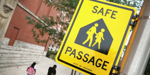 CHICAGO, IL - AUGUST 28: Students walk along a designated Safe Passage route to Laura Ward Elementary School on the Westside on August 28, 2013 in Chicago, Illinois. The Safe Passage program was started because parents were worried about their childrens safety while they walked to school across gang boundaries after the city closed 49 elementary schools and moved the students to nearby schools. Police, city workers and Chicago Public Schools personnel are posted along the route to provide 'safe passage' for the students. (Photo by Scott Olson/Getty Images)