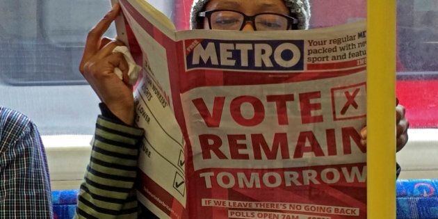 A woman reads a newspaper on the underground in London with a 'vote remain' advert for the BREXIT referendum, Britain June 22, 2016. REUTERS/Russell Boyce