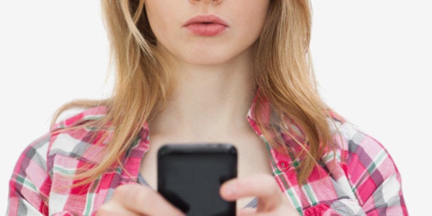 Annoyed woman using a mobile phone against a white background