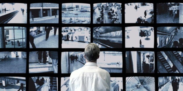 Man watching wall of surveillance screens