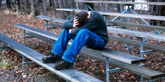Caucasian teenager sitting on bleachers with head down