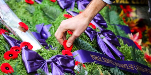 TORONTO, ON- NOVEMBER 11 A person places their poppy on one of the wreaths after the ceremony. Torontoians gather to remember those that made the ultimate sacrifice during Canada's wars at the Old City Hall Cenotaph. November 11, 2014. (David Cooper/Toronto Star via Getty Images)