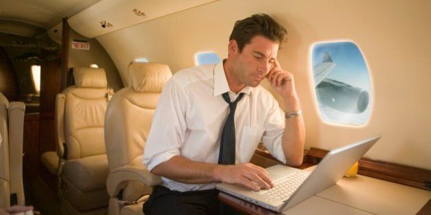 Businessman using laptop on airplane