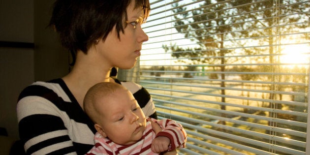 Young mother looking out from the window with her baby 2