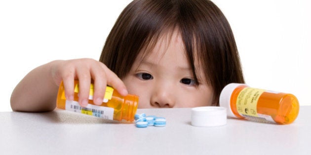 A young girl looks at a pile of pills that was left on a counter.