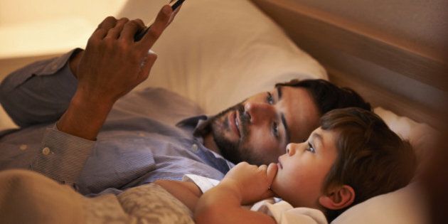 A father reading a bedtime story to his son from an e-reader