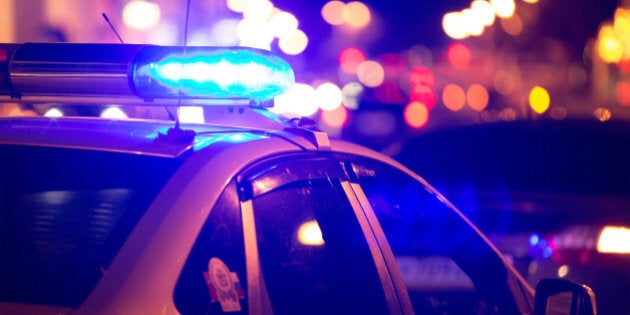 Blue light flasher atop of a police car. City lights on the background.