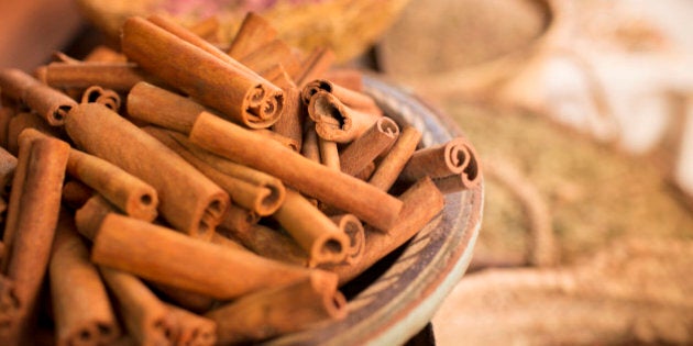 Cinnamon sticks on plate and other spices in background in spice market