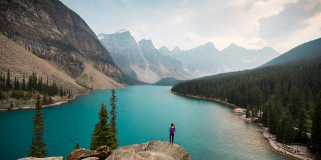 A woman standing on a scenic lookout overlooking Moraine Lake in Alberta, Canada.