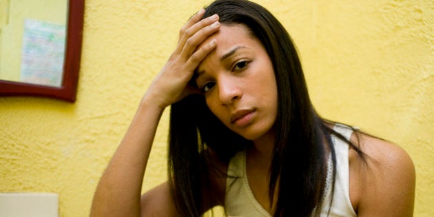 Worried Woman Sitting on Toilet Holding Home Pregnancy Test