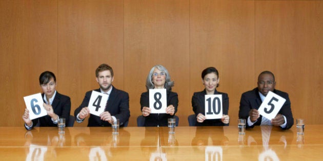 Executives at conference table holding score cards, portrait