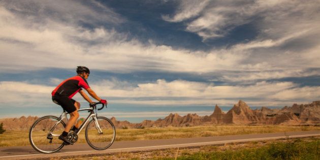 Man cycling on road in the morning in Badlands National Park, South Dakota.