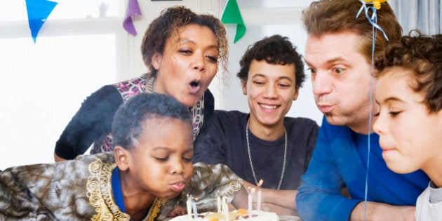 Family blowing out birthday cake candles.