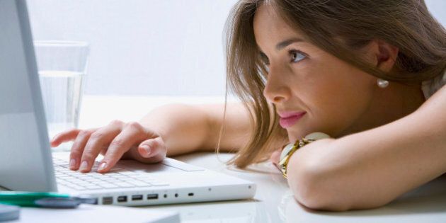 Mixed race businesswoman laying on desk using laptop