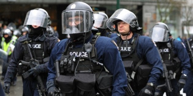 Armed riot police leave after confronting anti-Olympic protestors marching in downtown Vancouver on February 13, 2010. On the streets of Vancouver, around 200 anti-Olympic protestors clashed with riot police, smashing windows, kicking cars and throwing objects. The violence followed small-scale protests on the final leg of the Olympic torch relay Friday when around 100 demonstrators, upset over the financial and environmental impact of the Olympics, briefly blocked its route. AFP PHOTO/Mark RALSTON (Photo credit should read MARK RALSTON/AFP/Getty Images)