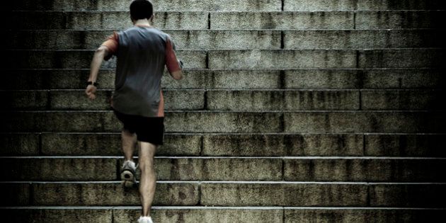 Athlete training on steep old worn concrete stairs - toned image for dramatic feel.
