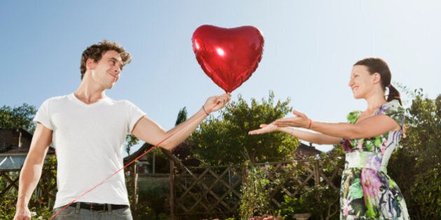 Man gives heartshaped balloon to woman.