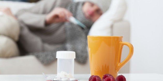 Man in bed having a cold and checking a temperature