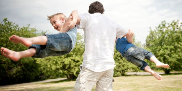 father spinning son's around in park