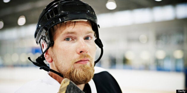 Portrait of ice hockey player standing on ice in hockey arena wearing helmet