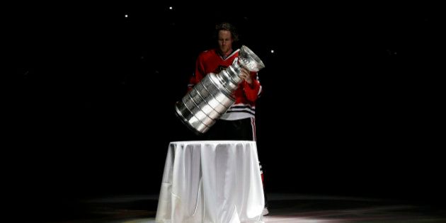 Chicago Blackhawks defenseman Duncan Keith carries out the Stanley Cup during a banner raising ceremony before an NHL hockey game between the Blackhawks and the Washington Capitals on Tuesday, Oct. 1, 2013, in Chicago. (AP Photo/Nam Y. Huh)