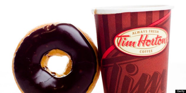 A cup of Tim Hortons Inc. coffee and doughnut are arranged for a photograph in Toronto, Ontario, Canada, on Wednesday, Aug. 3, 2011. Tim Hortons Inc. is a chain of franchise fast food restaurants that serve coffee drinks, tea, soups, sandwiches, donuts, bagels, and pastries. Photographer: Brent Lewin/Bloomberg via Getty Images