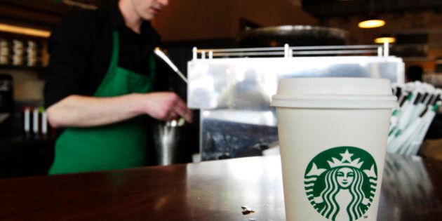 FILE - In this Friday, April 27, 2012, photo, a Starbucks drink waits for a customer to pick it up as barista Josh Barrow prepares another at left in Seattle. The world's biggest coffee chain is asking employees at cafes in the Washington, D.C., area to scribble the words