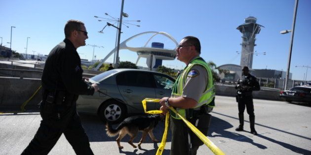 A K-9 officer (L) crosses a crime tape line on November 1, 2013 after a gunman reportedly opened fire at a security checkpointin Los Angeles International Airport. Police believe a gunman who opened fire at Los Angeles airport Friday acted alone, a police chief said, while not confirming reports that the shooter and one victim were killed. 'We believe at this point that there was a lone shooter, that he acted,' said Patrick Gannon, head of the LAX police force, saying he 'was the only person who was armed in this incident.' Seven people were injured, including six taken to hospital, said the head of the LA Fire Department James Featherstone, briefing reporters for the first time a couple of hours after the incident. AFP PHOTO/ROBYN BECK (Photo credit should read ROBYN BECK/AFP/Getty Images)
