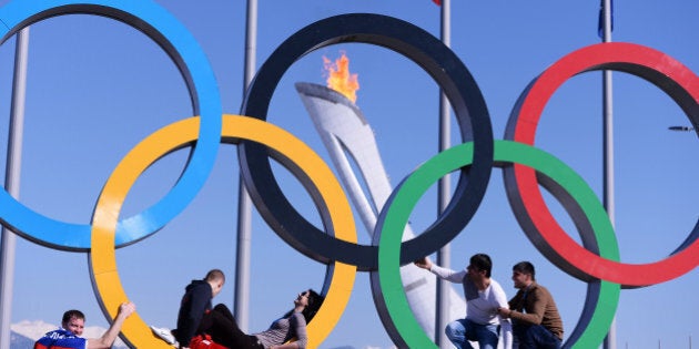 People pose in the Olympic Rings in the Olympic park during the Sochi Winter Olympics on February 15, 2014. AFP PHOTO / ANDREJ ISAKOVIC (Photo credit should read ANDREJ ISAKOVIC/AFP/Getty Images)