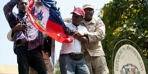 Haitian police remove protestors who tried to place the Haitian flag on the mast of the Consulate General of the Dominican Republic during a demonstration in Port-au-Prince on February 25, 2015, calling for the end of what protestors said was anti-Haitian sentiment in the Dominican Republic. The demonstrators also called for nonviolence and the end of racism. On February 10, a Haitian immigrant in the Dominican Republic was found hanged, reportedly lynched, from a tree in a park in Santiago. AFP PHOTO/ HECTOR RETAMAL (Photo credit should read HECTOR RETAMAL/AFP/Getty Images)