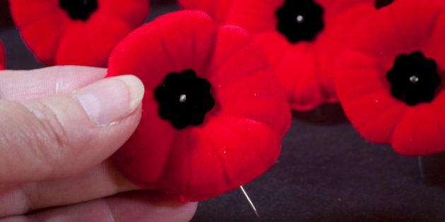 [UNVERIFIED CONTENT] The red poppy is a symbol of remembrance for all the men and women who fought in war. This design is Canadian. A hand is selecting a pin from many.