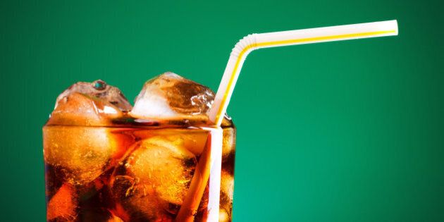 glass of cola with ice and straw on green background