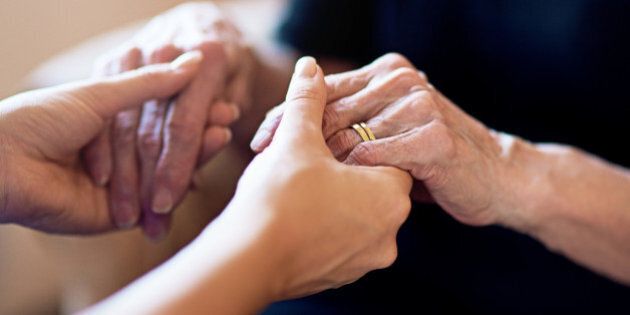Cropped shot of a person holding an elderly womanâs hands