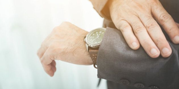 Close up of businessman in grey suit looking watch.