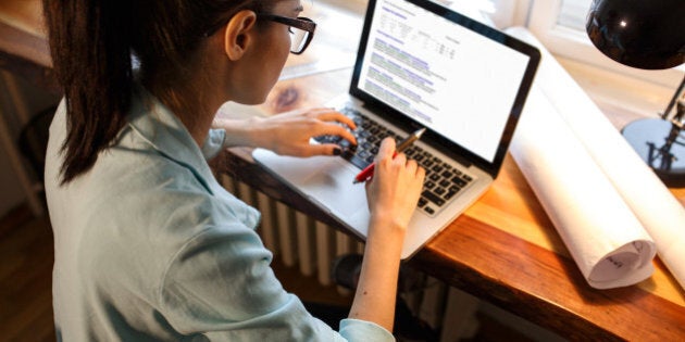 Young female blogger working at home.She sitting in her working room and typing something on laptop.