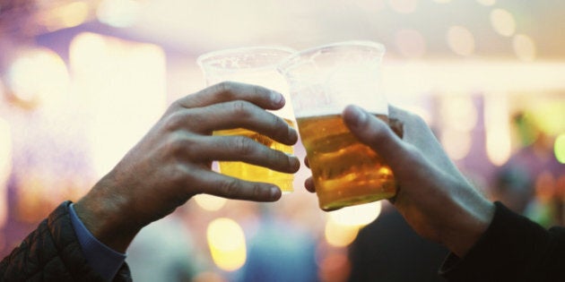 Two friends toasting to the good times with plastic cups of beer - Music Festival