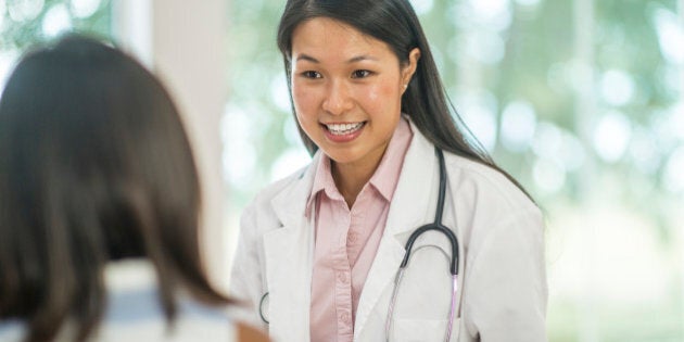 A doctor is talking to a little girl while she is at her checkup.