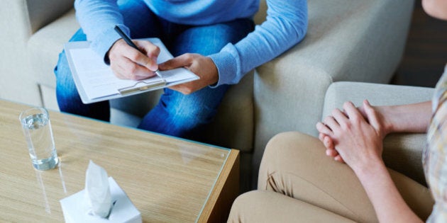 Male psychologist making notes during psychological therapy