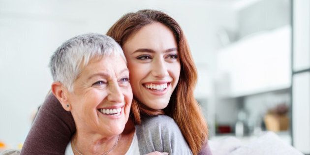 Young woman holding affectionately her mother, both are smiling happily, with copy space