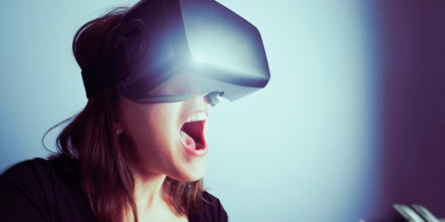 A mid-adult woman wearing a virtual reality headset, using a video game controller, totally involved in a video game. Mouth open, shouting with excitement; close-up, wide-angle image.