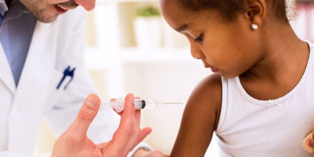 Doctor pediatrician injecting vaccine to cute african girl