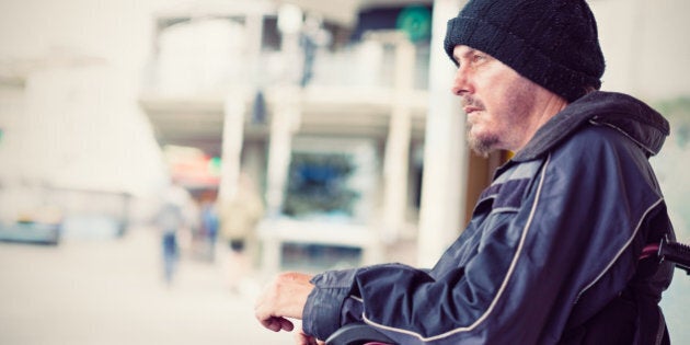 Homeless young invalid man sitting in wheelchair on the street