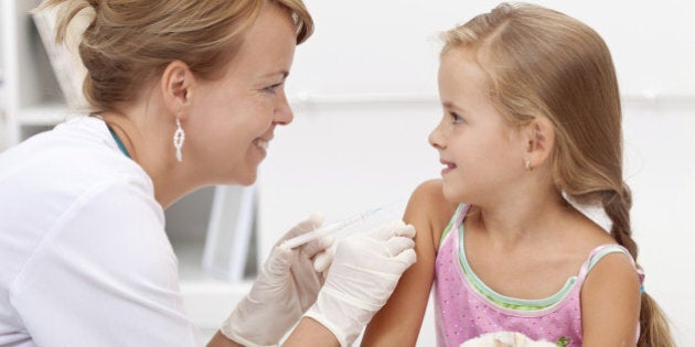 Brave little girl receiving injection or vaccine with a smile