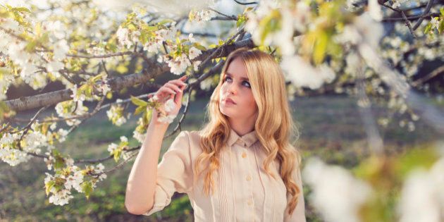 Portrait of a beautiful blonde enjoying the scents of a spring blossoms.