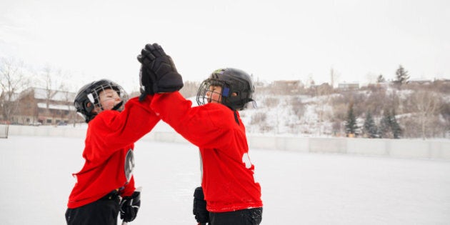 Ice hockey players giving high-five on rink