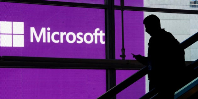 An attendee is silhouetted against a Microsoft Corp. poster as he rides an escalator at the Microsoft Developers Build Conference in San Francisco, California, U.S., on Wednesday, April 2, 2014. Microsoft Corp. is adding a voice-controlled digital assistant called Cortana to its Windows Phone software, seeking to match a feature that's already available in Apple Inc. and Google Inc. smartphones. Photographer: David Paul Morris/Bloomberg via Getty Images