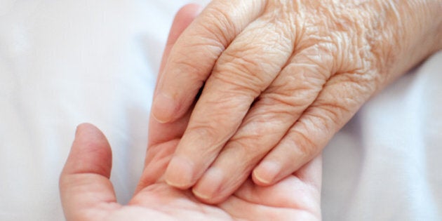 A young hand touches and holds an old wrinkled hand